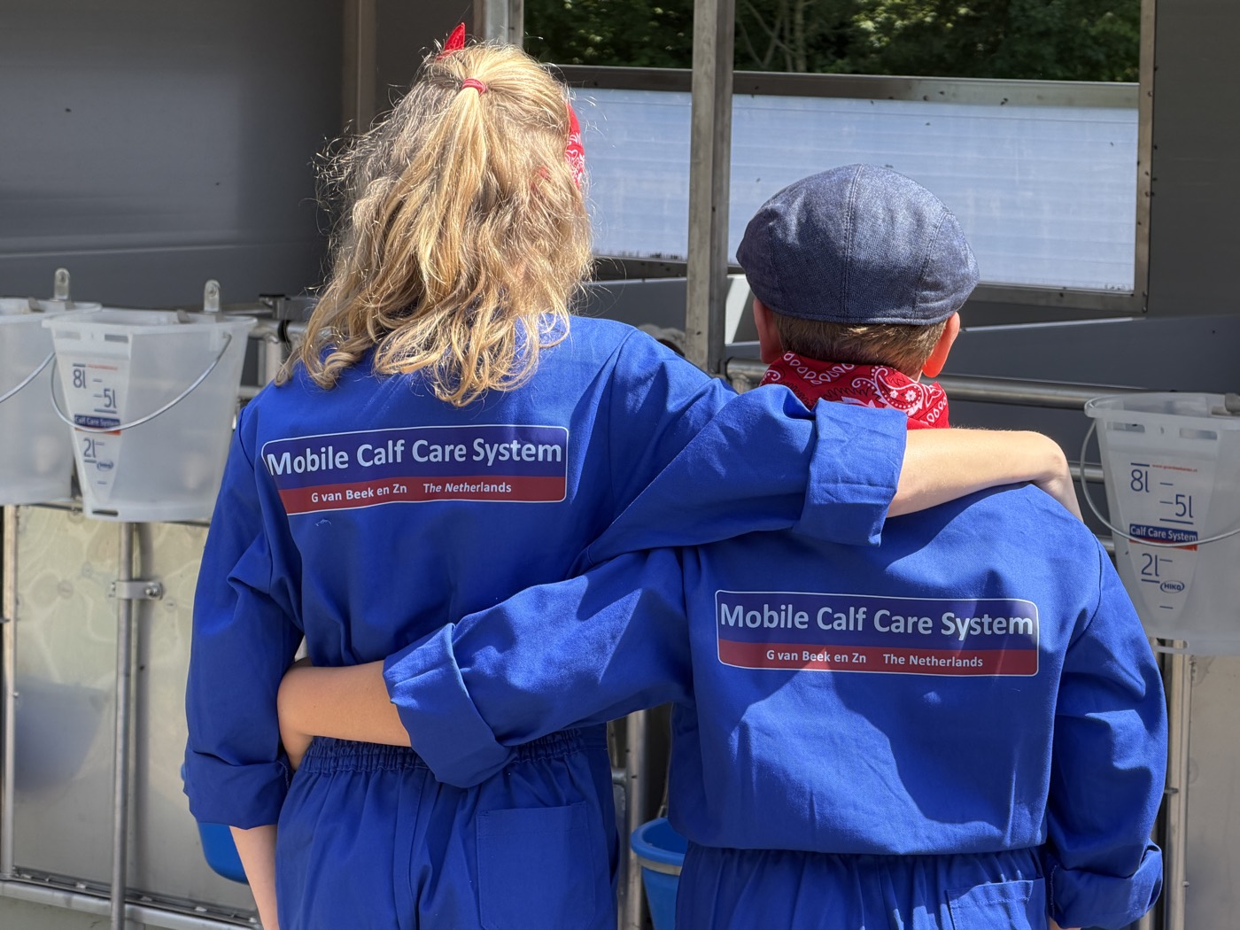 Deux utilisateurs en tenue Mobile Calf Care System devant l'enclos